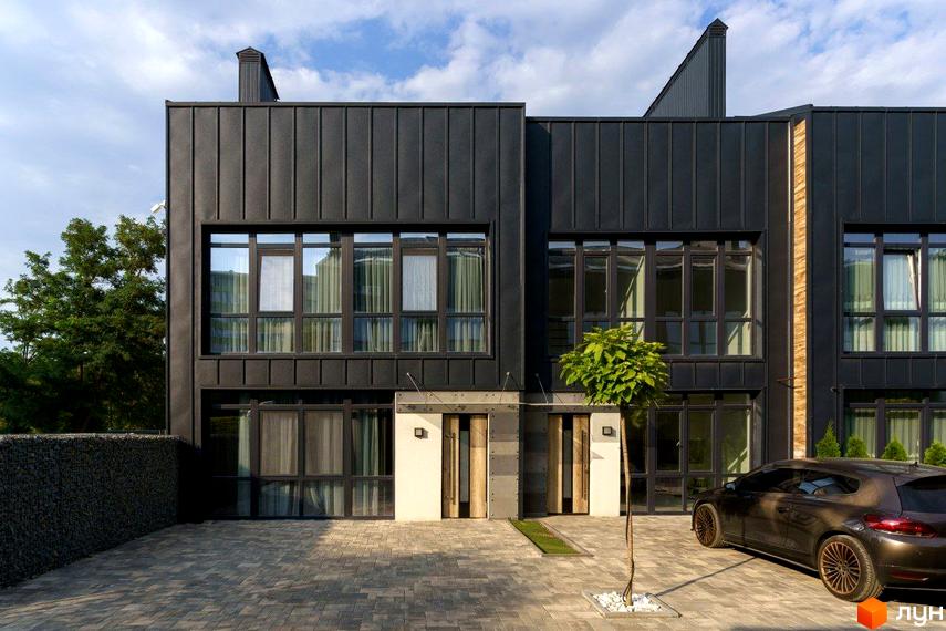 Таунхаус Black edition з чорним фасадом та великими вікнами, перед будинком вимощена доріжка та припаркований автомобіль.