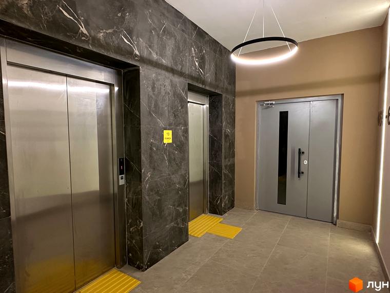 Сучасний хол з ліфтами та дверима у житловому комплексі ЖК СОУРЕНЖ. Елегантне освітлення створює затишну атмосферу.