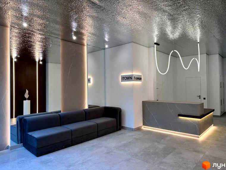 Холл житлового комплексу ITown ART Apartments з диваном, стійкою ресепшн та оригінальним освітленням. Просторий інтер'єр з оздобленням з мармуру та дзеркалами.
