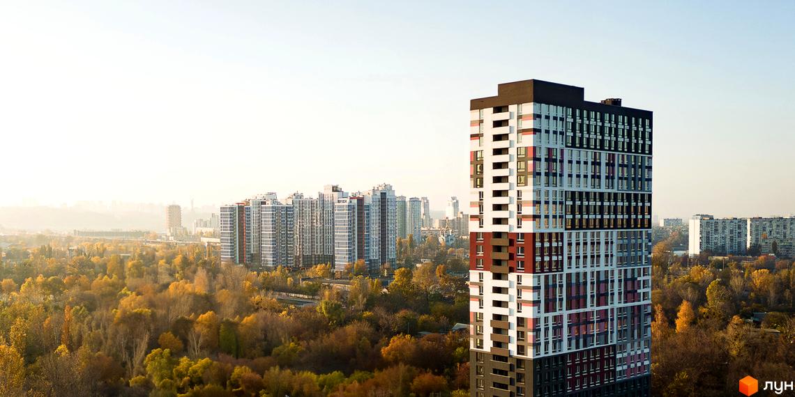 Вигляд на багатоповерховий будинок Будівельного проєкту Синергія Київ. Навколо будинку ростуть дерева з жовтим листям.