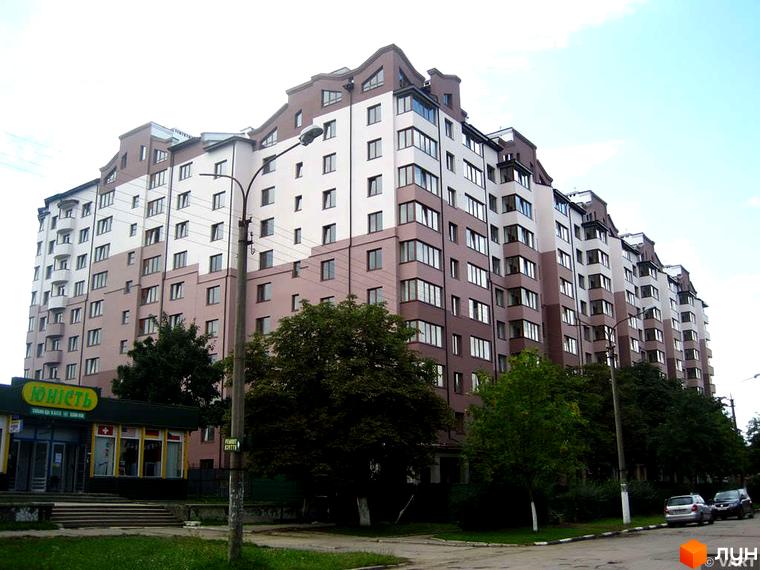 Зображення фасаду житлового комплексу Вишеньки. Багатоповерхова будівля з вікнами, поруч дерева та тротуар.
