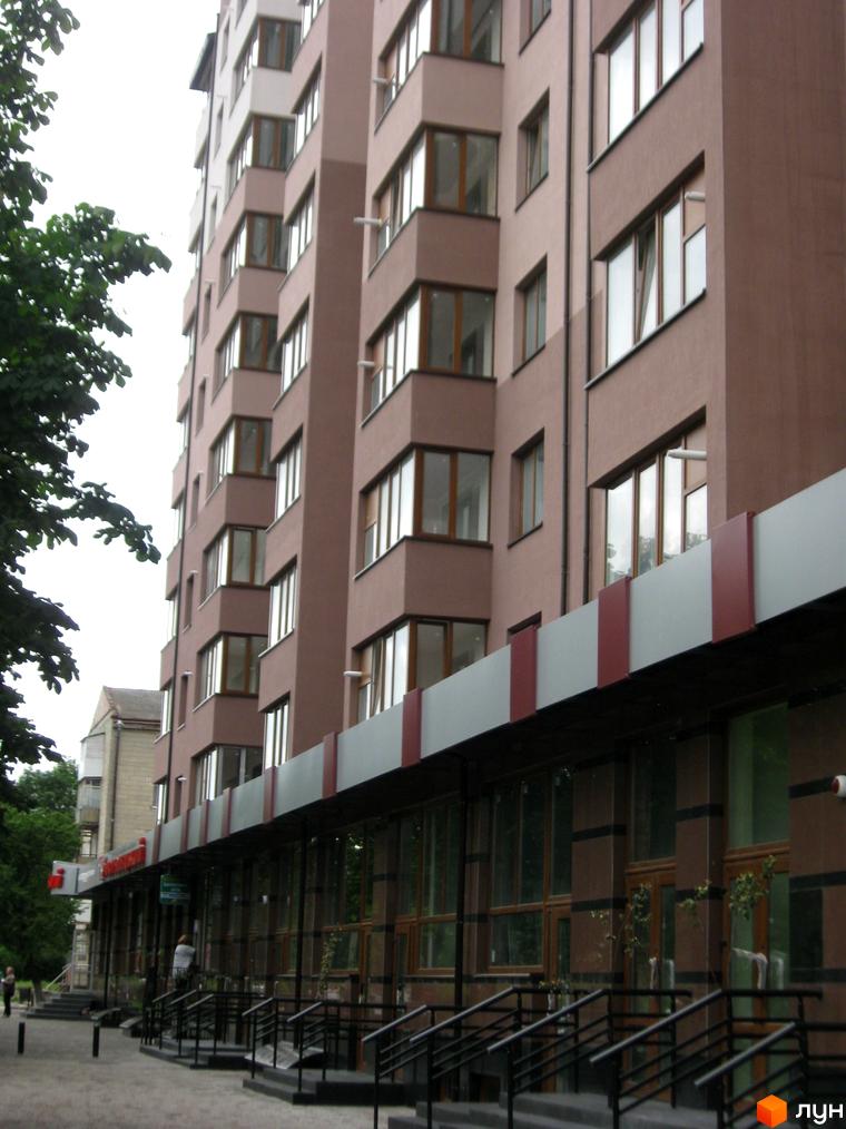 Зображення фасаду багатоповерхового будинку в Житловому комплексі Вишеньки. Вигляд з вулиці, видно вікна та балкони.