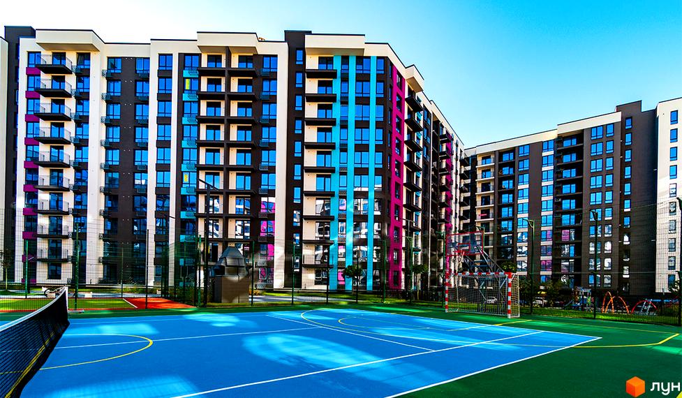Зовнішній вигляд житлового комплексу Family Plaza з яскравими фасадами та великою спортивною зоною для мешканців.
