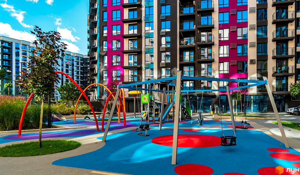 Зовнішній вигляд Новобудови Family Plaza з кольоровими фасадами. На передньому плані дитячий майданчик з різнокольоровим покриттям.