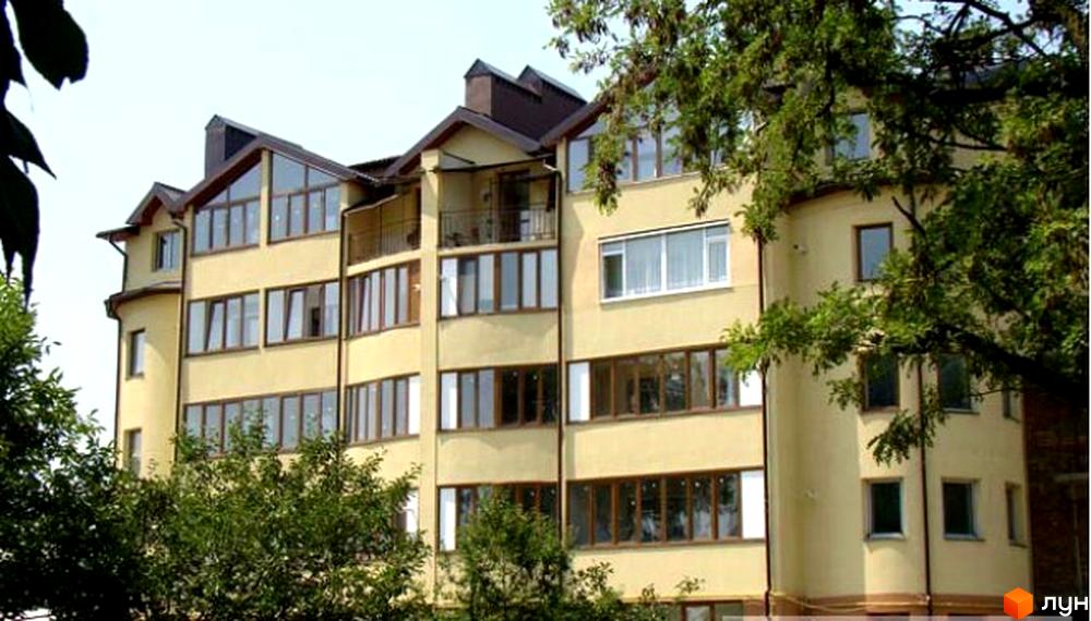 Зображення фасаду житлового будинку по вулиці Вербова, 32. Багатоповерхова будівля з великими вікнами та балконами, оточена зеленню дерев.