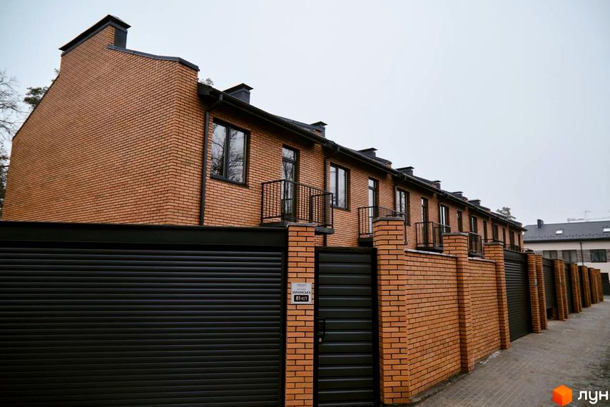 Таунхауси „Позітано Центр 2“ з цегляним фасадом та кованими балконами, огороджені цегляним парканом з воротами.