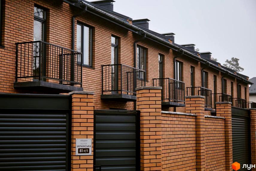 Таунхауси „Позітано Центр 2“ з цегляним фасадом та чорними балконами. Огороджена територія з воротами.