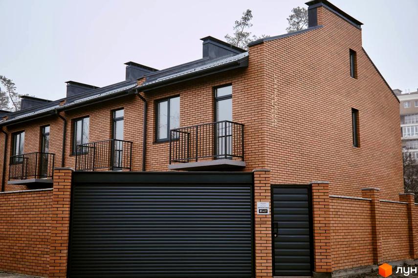 Зовнішній вигляд таунхаусів Позітано Центр 2 з цегляним фасадом та балконами. Прибудинкова територія включає паркан та ворота.