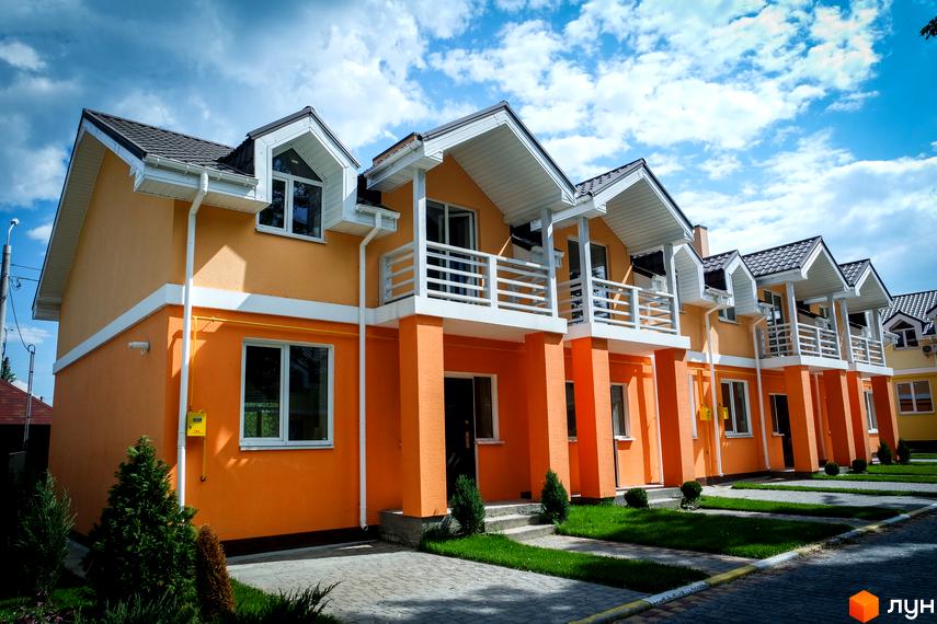 Вигляд будинків в Котеджному містечку Sun City. Двоповерхові котеджі з балконами, пофарбовані в помаранчевий колір, з зеленими насадженнями на подвір'ї.