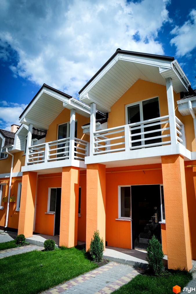 Фото Котеджного містечка Sun City: двоповерхові котеджі з балконами, пофарбовані в жовтий колір. Перед будинками зелені газони та тротуарна плитка.