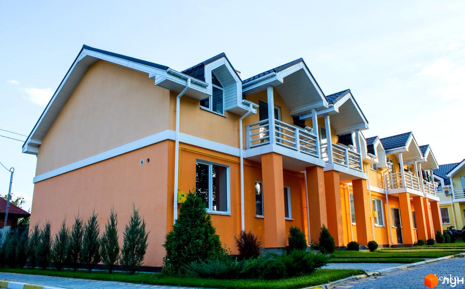 Фото Котеджного містечка Sun City: двоповерхові будинки з балконами, пофарбовані в помаранчевий та бежевий кольори. Навколо будинків зелені насадження.