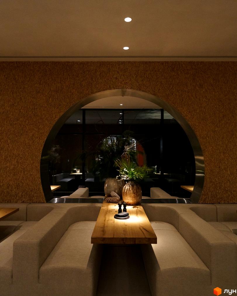 Інтер'єр апарт-комплексу Mountain Residence з диванами та столом. Дизайн інтер'єру з аркою та рослинами.