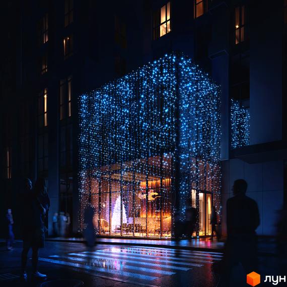 Житловий комплекс Avalon Up вночі, фасад будівлі прикрашений синіми гірляндами. Навколо будівлі видно вулицю та пішохідний перехід.