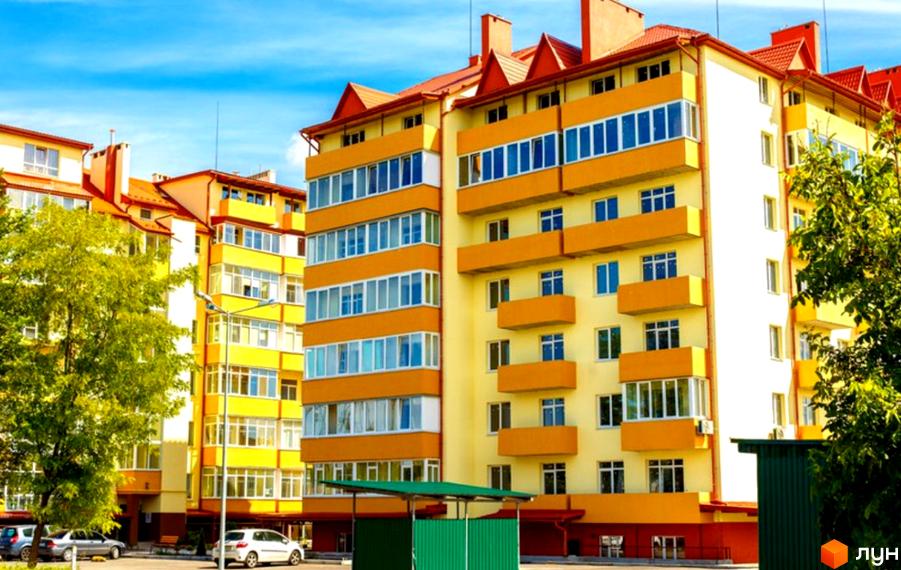 Зображення фасаду Житлового комплексу Чабани квартал. Багатоповерховий будинок жовтого кольору з помаранчевими вставками, зелені дерева поруч.