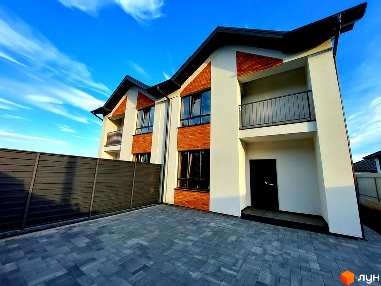 Фасади дуплексів Woodland Hill з білою штукатуркою та цеглою, чорні вікна та балкони. Перед будинком брукований двір та темна огорожа.