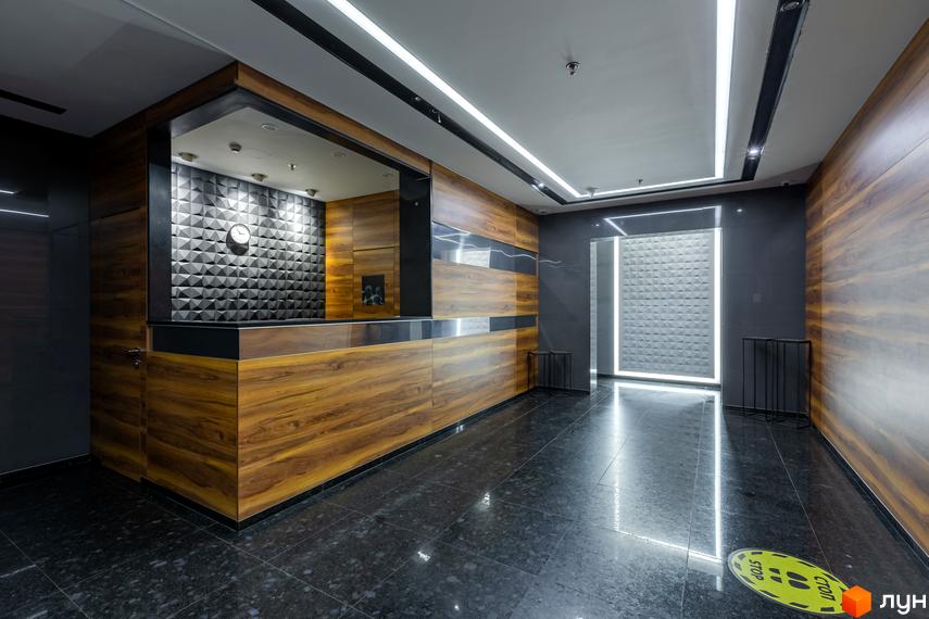 Сучасний вхід до житлового комплексу Smart Plaza Polytech з оформленням у темних тонах і дерев'яними елементами.