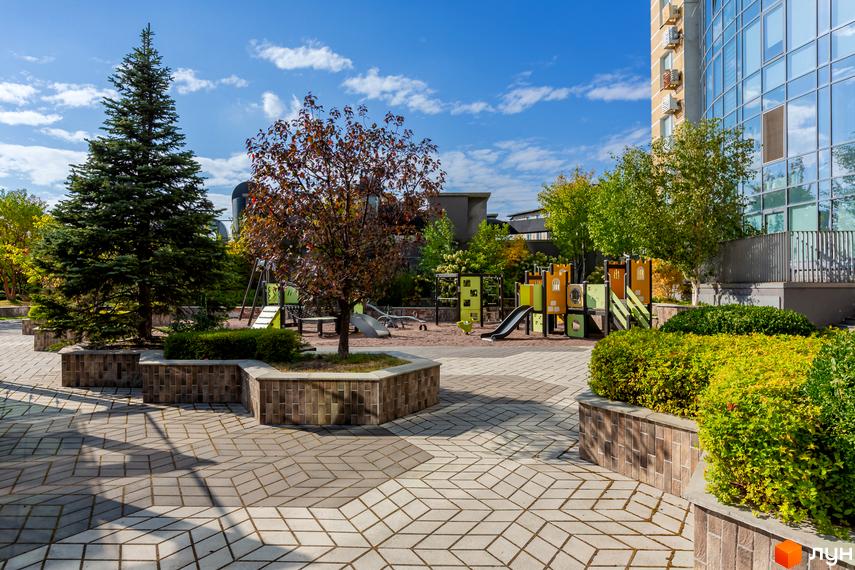 Сучасний будинок житлового комплексу Smart Plaza Polytech з прибудинковою територією та дитячим майданчиком.