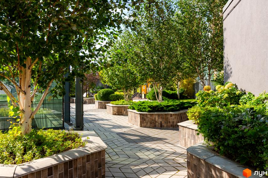 Сучасний житловий комплекс Smart Plaza Polytech з доглянутою прибудинковою територією, зеленими насадженнями та пішохідними доріжками.