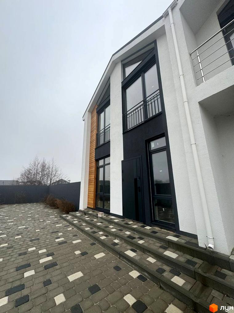 Сучасний дуплекс Family House з панорамними вікнами та дерев'яними вставками, вимощений двір з бруківки.