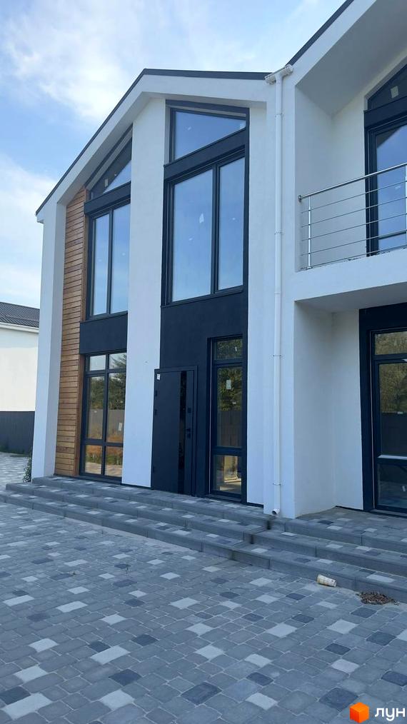 Дуплекси Family House: білий будинок з великими вікнами та дерев'яною обробкою. Перед будинком викладена бруківка та сходи.