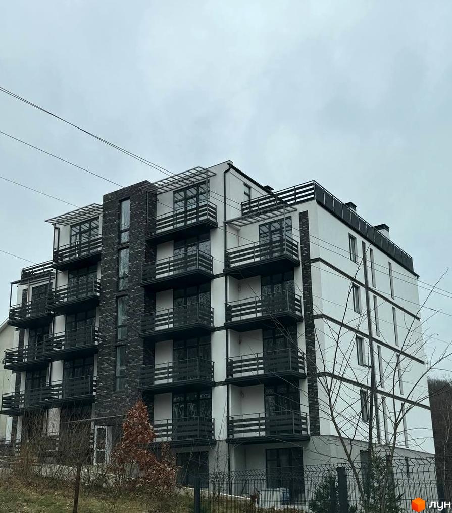 Багатоповерховий житловий комплекс за адресою вул. Курортна, 26, з білим фасадом, темними балконами та прилеглою територією з рослинністю.