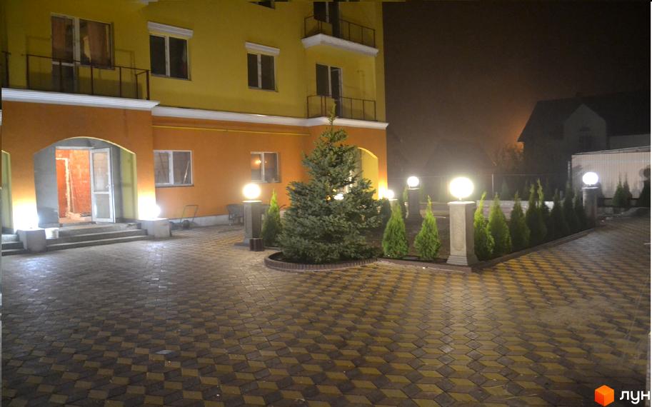 Зовнішній вигляд будинку в Житловому комплексі Петровский дворик. На прибудинковій території розташовані дерева та декоративні ліхтарі.