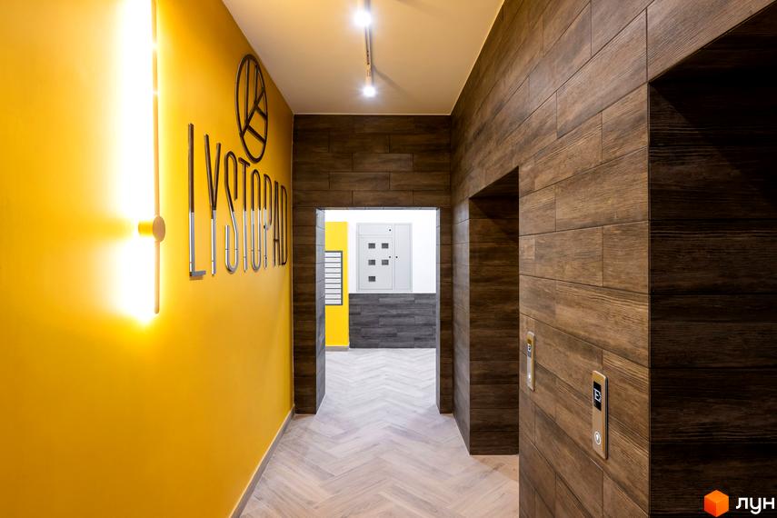 Дизайн вхідної групи ЖК Lystopad з жовтими стінами та дерев'яними елементами. Сучасний коридор з ліфтовим холом.