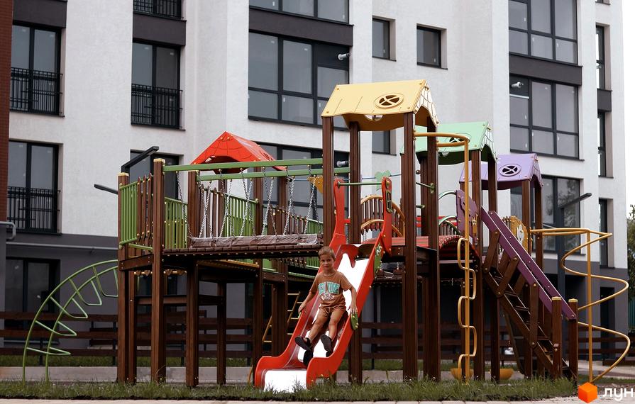 Дитячий майданчик біля житлового комплексу Містечко Мануфактура. Хлопчик спускається з гірки на сучасній дитячій площадці.