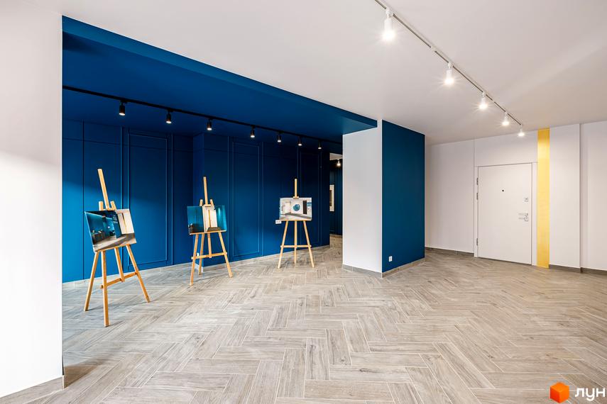 Житловий комплекс HydroPark DeLuxe. Інтер'єр з синіми стінами, картинами на мольбертах та білою стелею. Паркетна підлога викладена ялинкою.