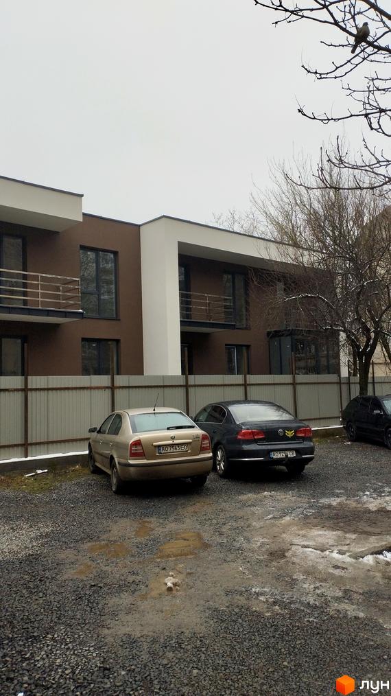 Зовнішній вигляд будинку житлового комплексу на вул. Володимирська, 65а, з паркуванням та деревами. Сучасна архітектура новобудови.