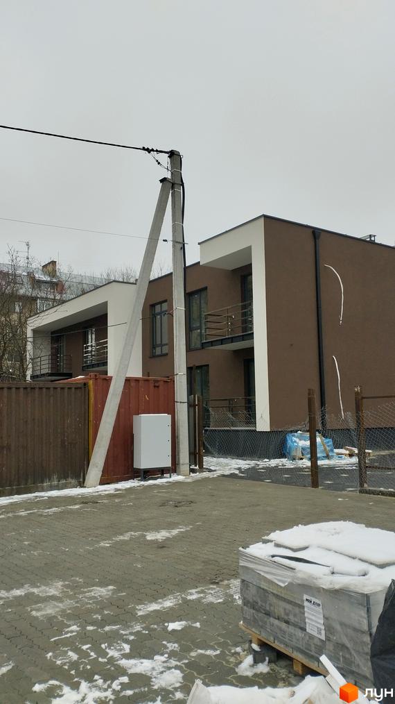 Будинок з коричневими та білими фасадами на вулиці Володимирська, 65а, з бетонною опорою та парканом на прибудинковій території.