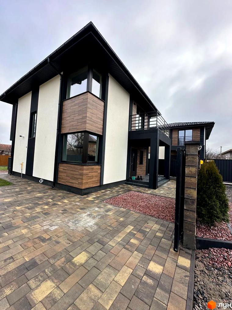 Сучасний двоповерховий будинок з дерев'яним оздобленням фасаду та бруківкою на подвір'ї на вул. Яблунська, 20.