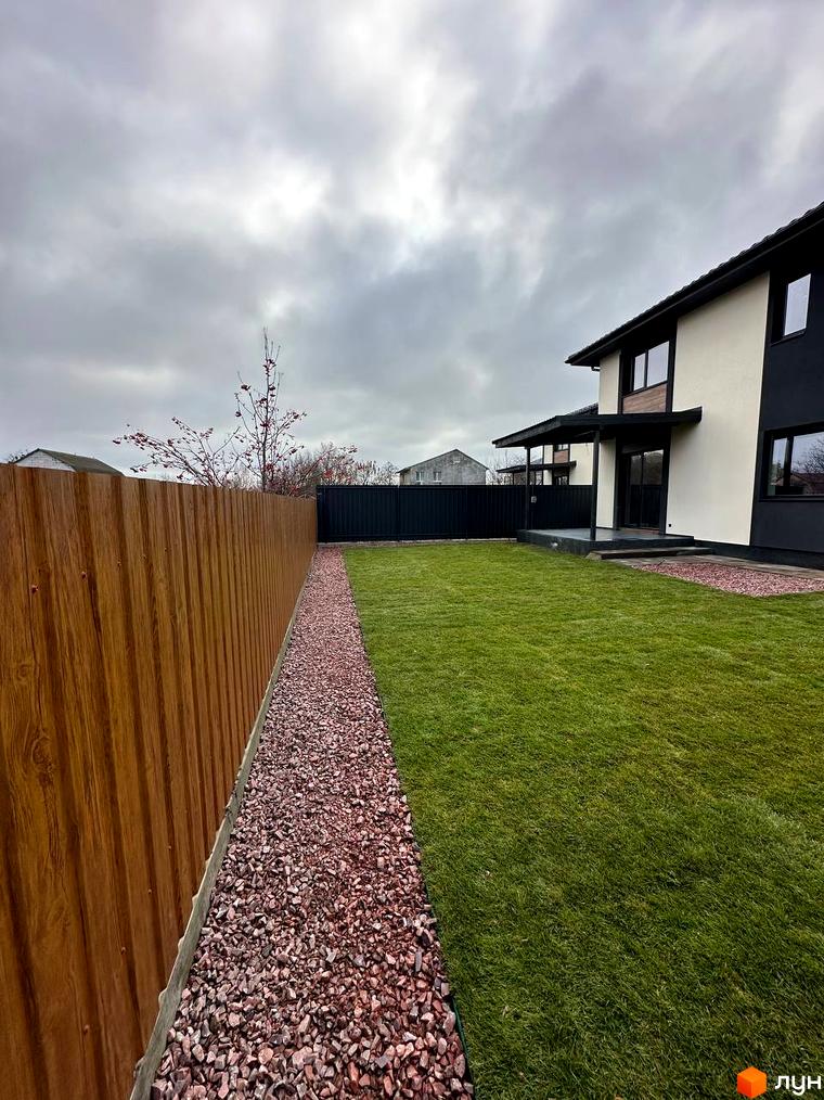 Зовнішній вигляд будинку на вул. Яблунська, 20, з акуратним газоном та дерев'яним парканом. Територія навколо будинку облаштована гравієм та зеленою травою.
