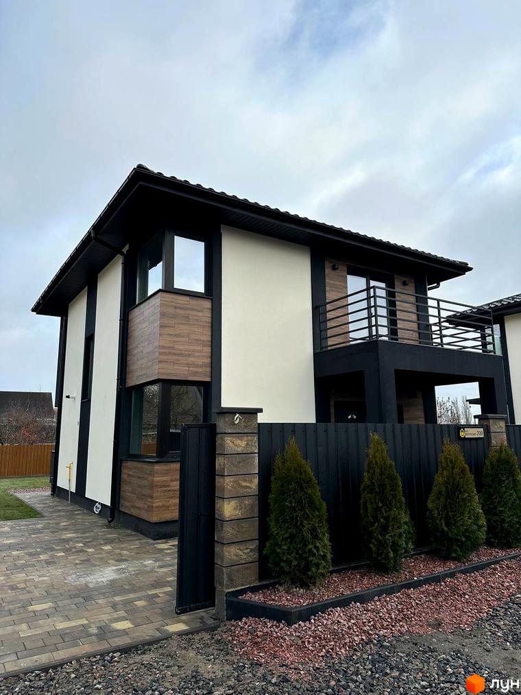 Сучасна двоповерхова новобудова з чорною огорожею та зеленими туями на вулиці Яблунська, 20. Прибудинкова територія з бруківкою та декоративним каменем.