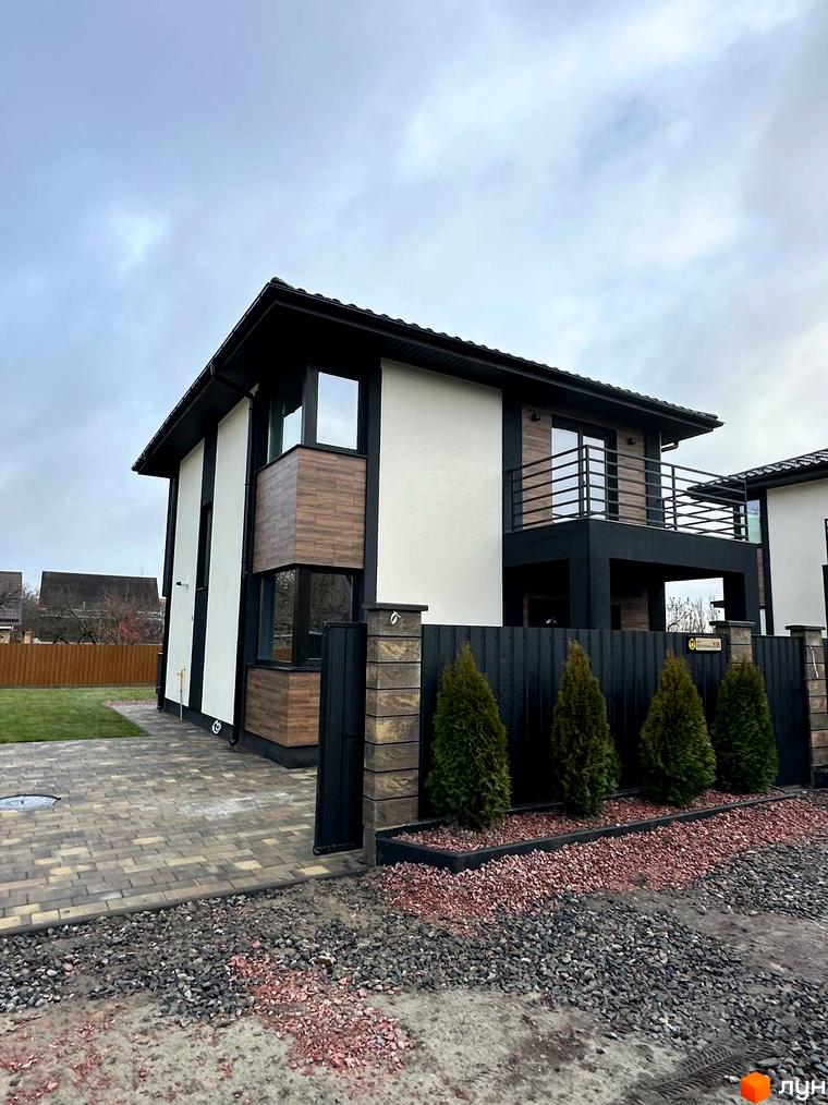 Фасад будинку на вул. Яблунська, 20 з елементами дерев'яної обшивки та великими вікнами. Прибудинкова територія з бруківкою та зеленими насадженнями.