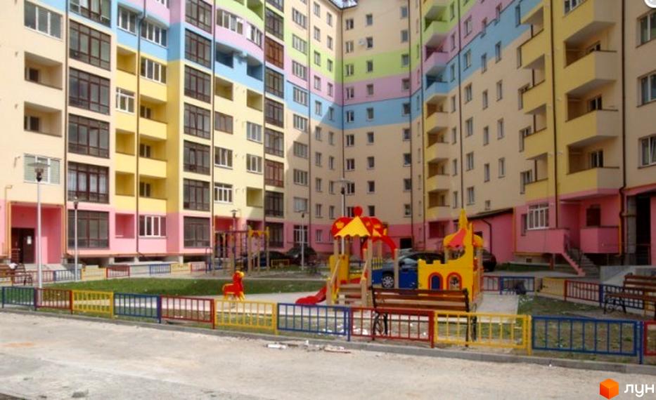 Зображення фасаду та дитячого майданчика Житлового комплексу Новий Станіслав. Багатоповерховий будинок з кольоровими стінами та зоною для ігор.
