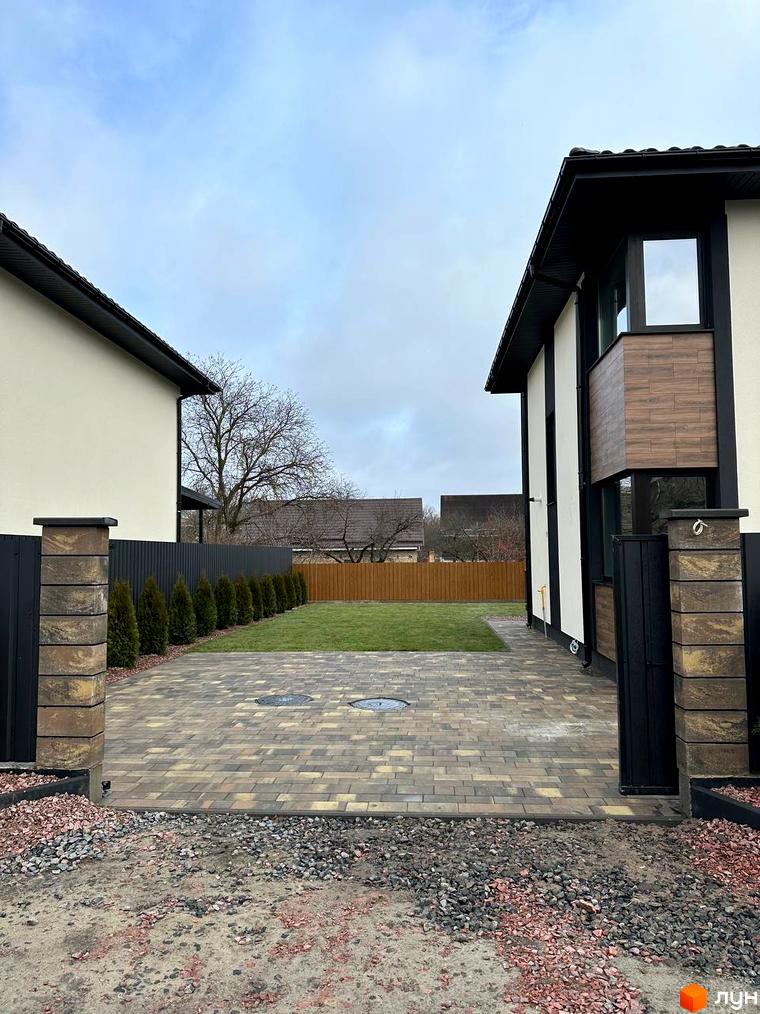 Зовнішній вигляд будинку на вул. Яблунська, 20, з бруківкою та газоном. Опис новобудови та прибудинкової території.