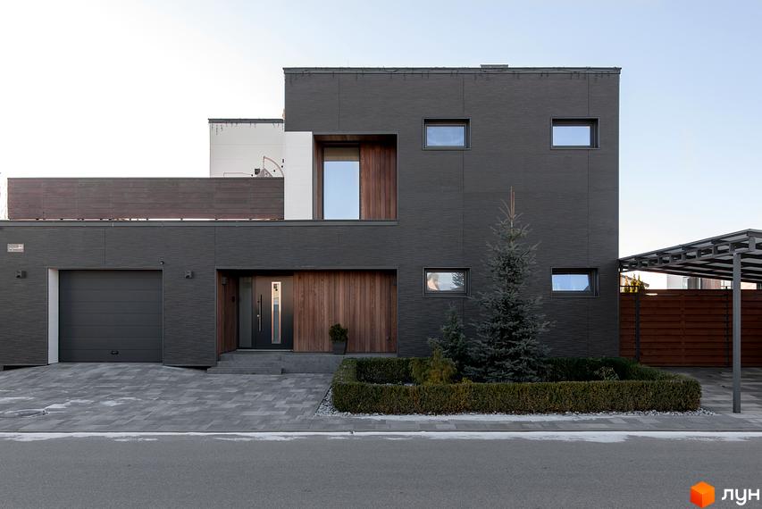 Котеджне містечко КМ Balaton Village. Сучасний двоповерховий будинок з темним фасадом, великими вікнами та дерев'яними елементами. Прибудинкова територія з доглянутим газоном та ялинками.