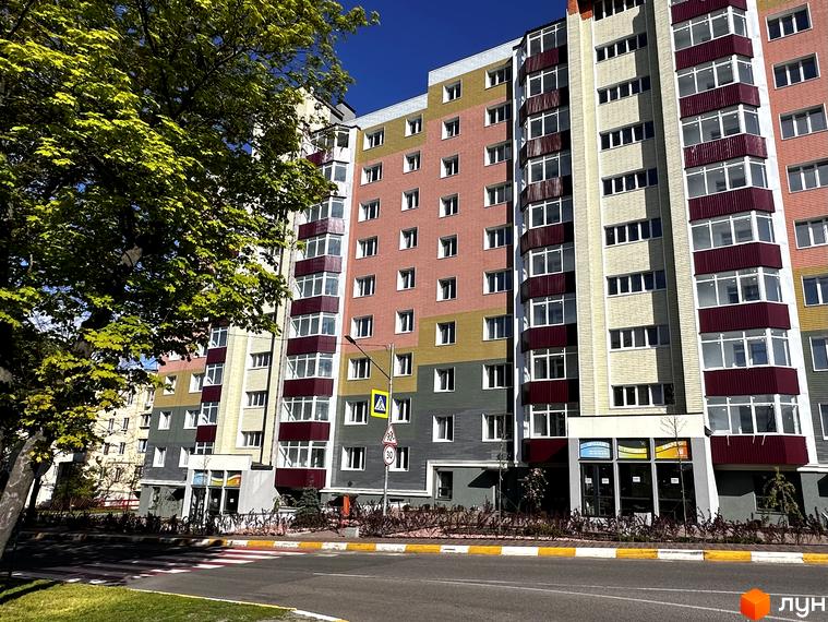 Житловий комплекс Всі Свої - фасади будівель у яскравих кольорах, балкони з бордовими перилами, зелена зона та дорога перед будинком.