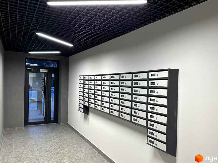 Вхідна група житлового комплексу Всі Свої з поштовими скриньками на стіні. Вхідні двері та коридор з лінійним освітленням.