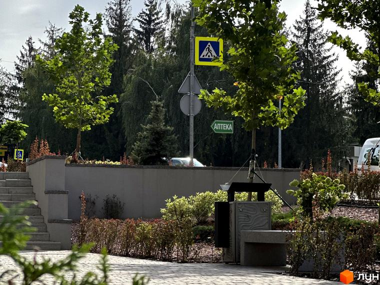 Житловий комплекс Всі Свої. Зовнішній вигляд будинку та прибудинкової території з деревами, пішохідним переходом та аптекою.