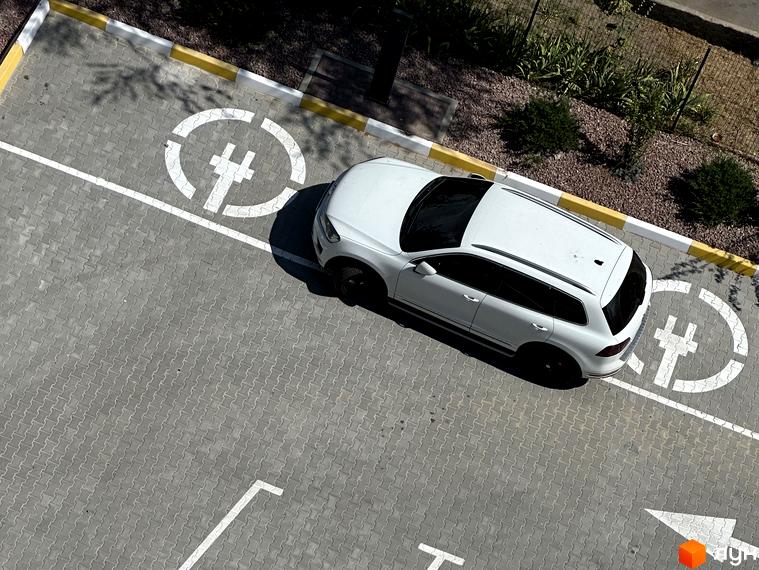 Парковка біля ЖК Всі Свої з позначками для електромобілів. Білий кросовер припаркований на спеціальному місці для зарядки.