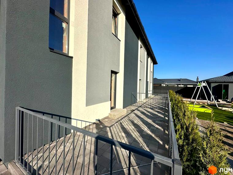 Таунхауси COMFORT RESIDENCE з сірим та бежевим фасадом, огородженою терасою та зеленим подвір'ям із дитячим майданчиком.