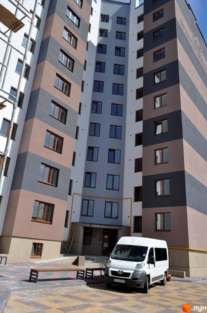 Зовнішній вигляд багатоповерхового будинку на вул. Мазепи, 141-143. На передньому плані прибудинкова територія з лавкою та автомобілем.