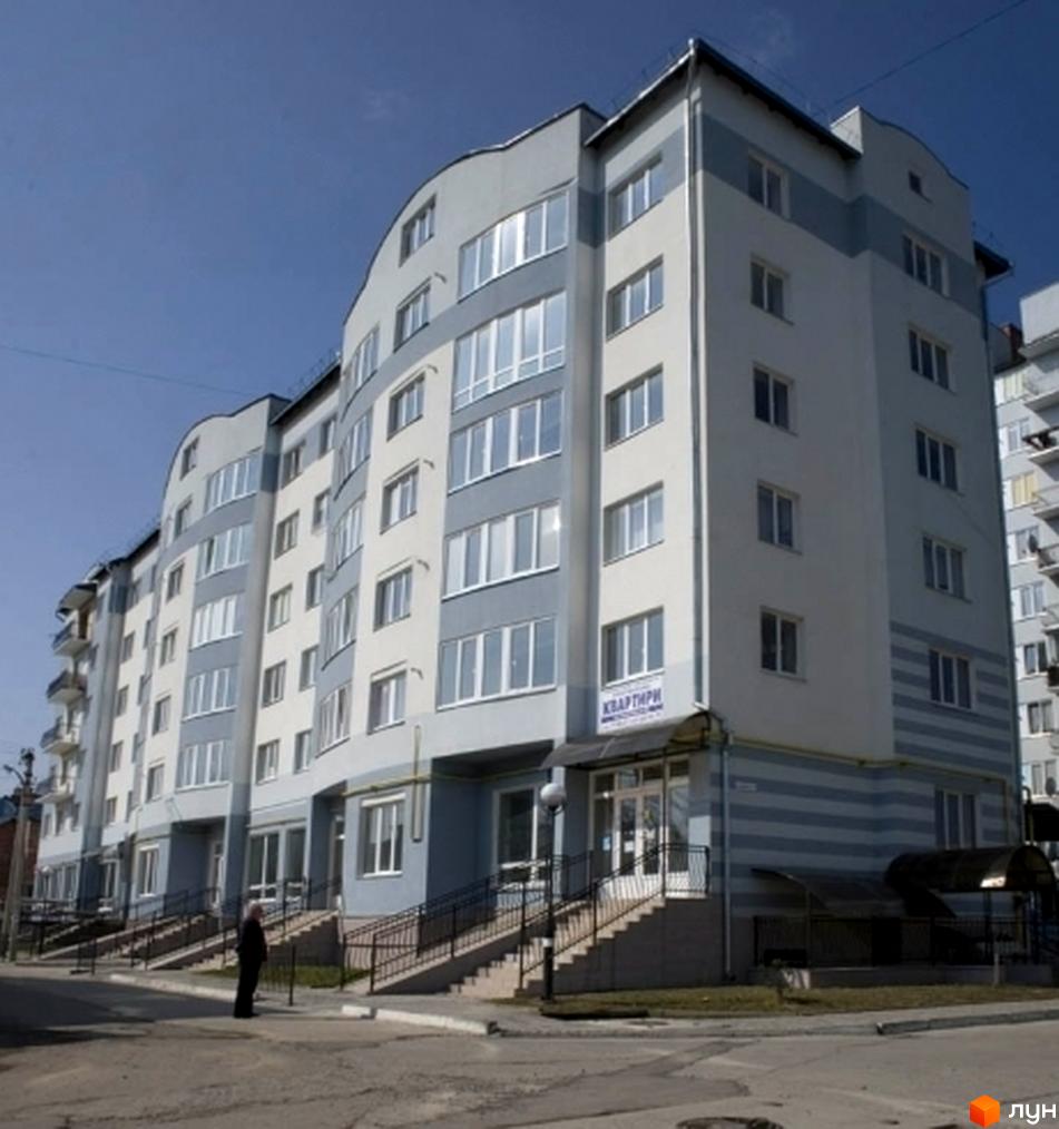 Зображення фасаду багатоповерхового будинку на вулиці Чорноти. Світла будівля з великими вікнами та облаштованою прибудинковою територією.