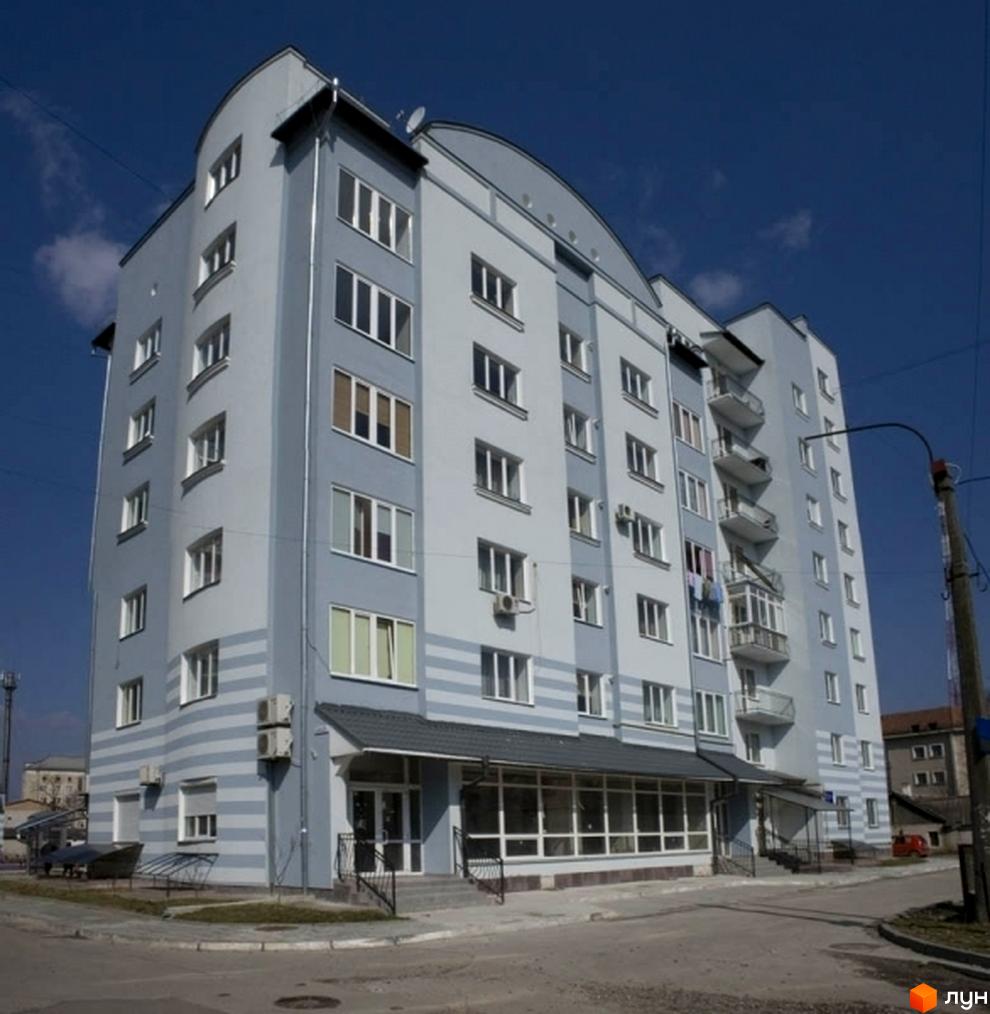 Зображення багатоквартирного будинку на вулиці Чорноти. Світла будівля з великими вікнами та балконами на тлі блакитного неба.