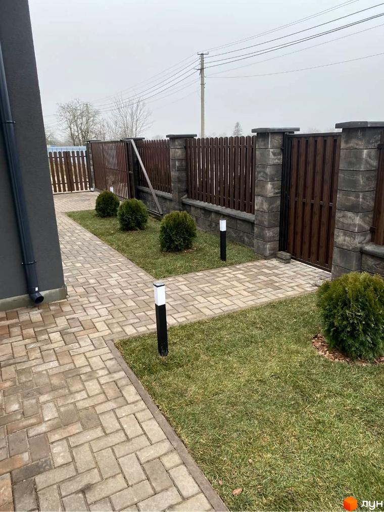 Котеджне містечко КМ Focus Village: огороджена територія з бруківкою та зеленими насадженнями. Сучасний паркан та освітлення біля будинку.