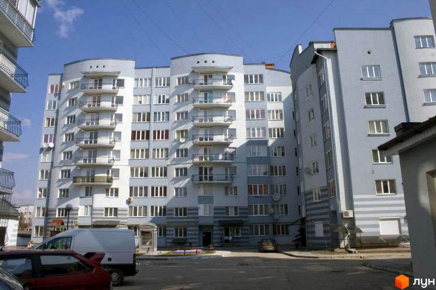 Фото фасаду багатоповерхового будинку на вулиці Чорноти. На передньому плані видно частину прибудинкової території та автомобілі.