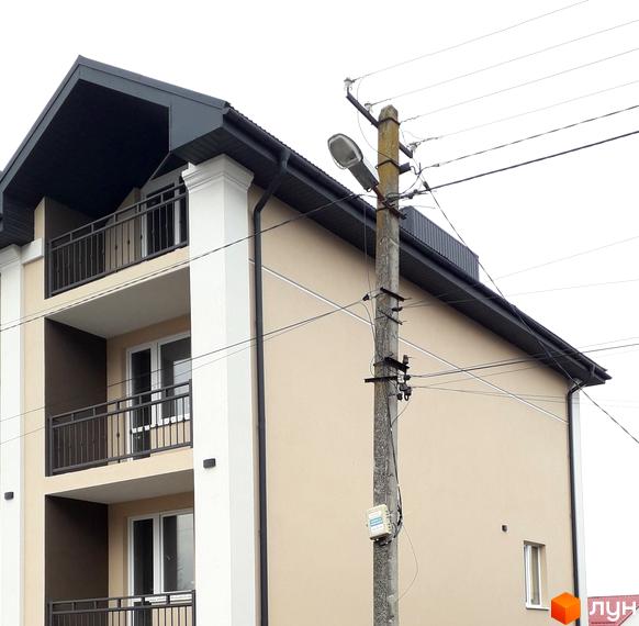 Будинок житлового комплексу на вулиці Безкоровайного, 5, з балконами та вікнами. Поруч розташована електроопора з ліхтарем.