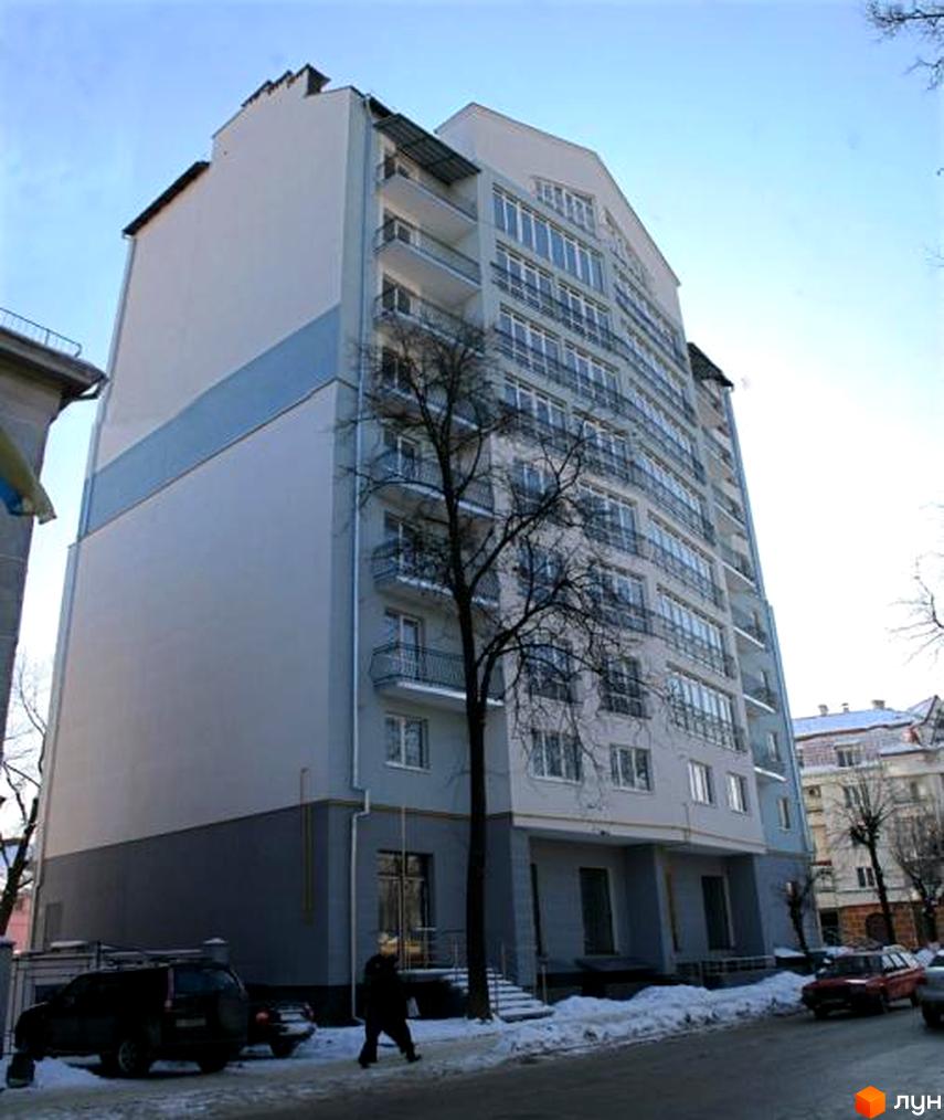 Зображення багатоповерхового будинку на вулиці Чорновола, 67-69. Фасад будівлі світлий, з балконами та великими вікнами, перед будинком видно дерева та сніг.